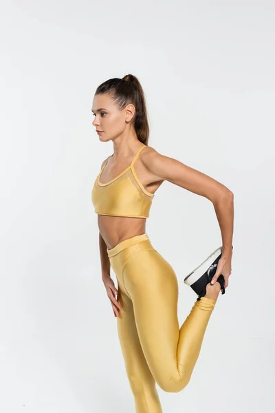 Mulher em treinamento de roupas de fitness e alongamento perna no branco, conceito de motivação fitness — Fotografia de Stock