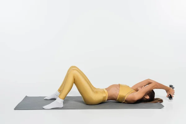 Mulher em meias e treinamento de roupas de fitness com halteres no tapete de fitness no fundo branco — Fotografia de Stock