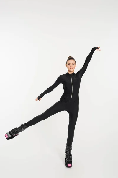 Jumping boots, white background, sportswoman in black jumpsuit and kangoo jumping shoes — Stock Photo