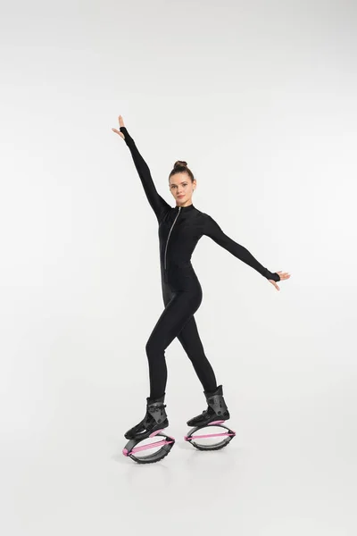 Sportswoman in boots for jumping, woman in black jumpsuit and kangoo jumping shoes — Stock Photo
