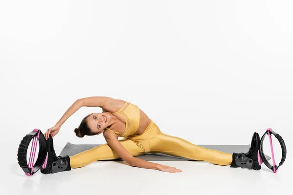 Flexible Frau in aktiver Kleidung beim Training auf Fitnessmatte, Kangoo-Sprungschuhen, durchtrainiertem Körper, Sport — Stockfoto