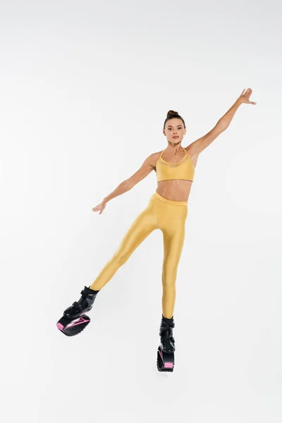 Donna energica in scarpe kangoo jumping corpo tonico, motivazione ed equilibrio, sfondo bianco — Foto stock