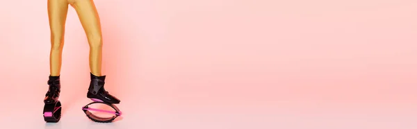 Springstiefel, beschnitten, Frau in Kangu-Springschuhen, rosa Hintergrund, Motivation, Banner — Stockfoto