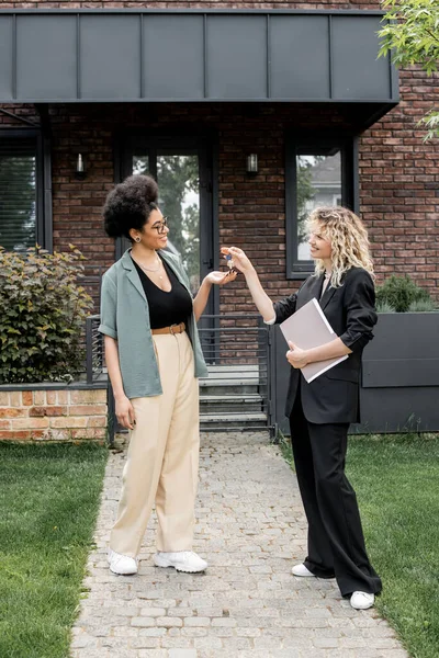 Happy african american woman taking key from new cottage from real estate agent — Stock Photo