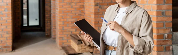 Cropped view of african american real estate agent holding folder and pen in new house, banner — Stock Photo