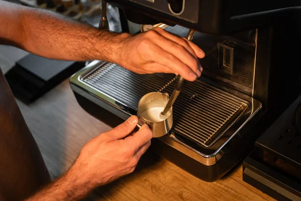Высокий угол зрения бариста пенящегося молока на кофеварке во время работы в кафе — стоковое фото