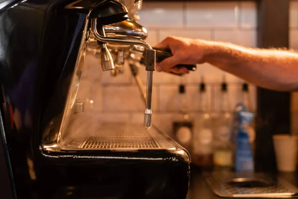 Vista cortada de barista desfocado usando máquina de café perto de vapor e iluminação no café — Fotografia de Stock