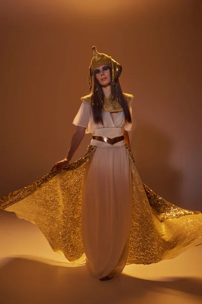 Volle Länge der Frau in ägyptischer Kleidung mit elegantem Rock, während sie auf braunem Hintergrund steht — Stockfoto