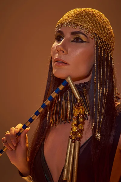 Портрет жінки в стильному єгипетському вигляді тримає чуття, позує ізольовано на коричневому — стокове фото