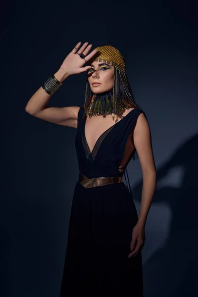 Красива жінка в єгипетському макіяжі і позує і дивиться на камеру на синьому фоні — стокове фото
