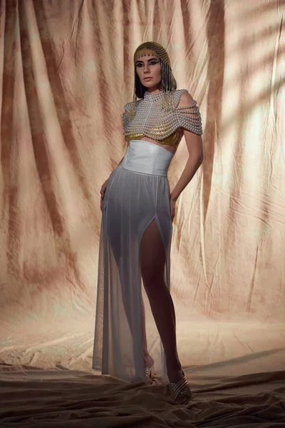 Volle Länge der eleganten brünetten Frau in ägyptischer Kleidung posiert auf abstraktem Hintergrund — Stockfoto