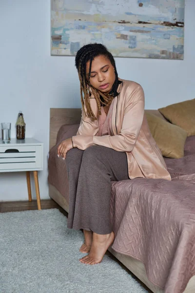 Donna afroamericana seduta sul letto, sensazione di malessere, tristezza e ansia, stress, camera da letto moderna — Foto stock