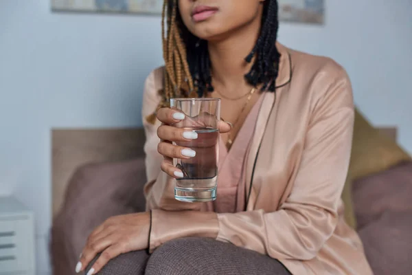 Mujer afroamericana sosteniendo vaso de agua y píldoras hormonales, ultrasonido en el telón de fondo, dormitorio - foto de stock