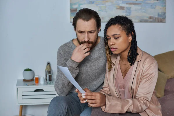 Worried multicultural couple looking at ultrasound photo, black woman and man, pregnancy, decision — Stock Photo