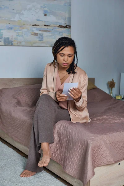 Entscheidungsfindung, afrikanisch-amerikanische Frau sitzt auf dem Bett und schaut Ultraschall-Foto, Schlafzimmer — Stockfoto