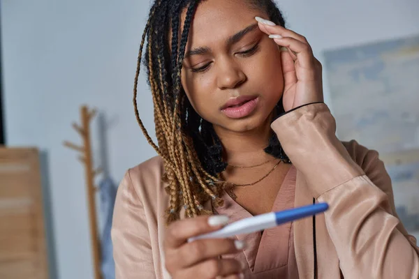 Concepto de aborto, mujer afroamericana que mira la prueba de embarazo y toma de decisiones, incertidumbre - foto de stock