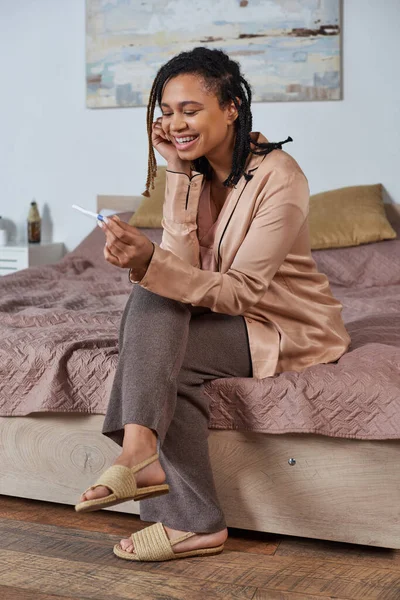 Cheerful african american woman looking at pregnancy test, positive result, expectation, future — Stock Photo