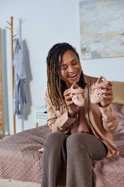Happy african american woman and bearded man holding baby shoes, future parents, expectation, cute — Stock Photo