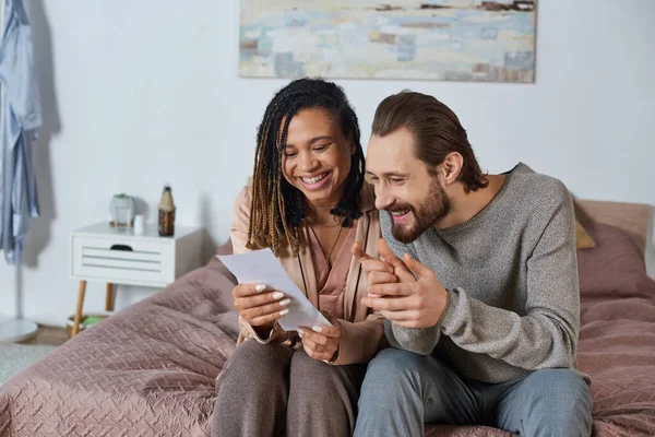 Happy interracial husband and wife looking at ultrasound scan, future parents, pregnant woman — Stock Photo