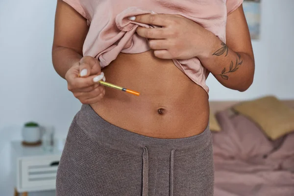 Femme afro-américaine faisant des injections hormonales dans le ventre, tatouage, concept de grossesse, cultivé — Photo de stock