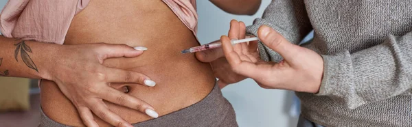Homme cultivé faisant des injections hormonales dans le ventre de la femme afro-américaine, tatouage, fertilité, bannière — Photo de stock