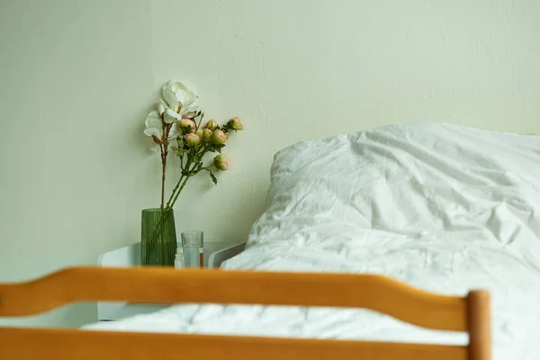 Hôpital salle privée, bouquet de fleurs dans un vase près du lit, verre d'eau, hospitalisation, chambre — Photo de stock
