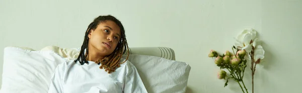Triste donna afroamericana sdraiata in reparto privato, fiori, ospedale, concetto di aborto spontaneo, banner — Foto stock