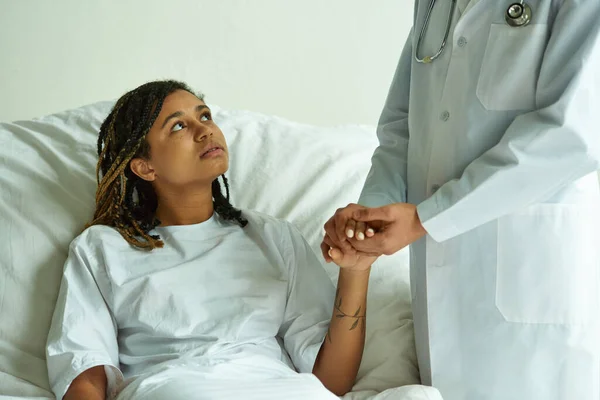 Doctor in white coat holding hand of african american woman, private ward, miscarriage concept — Stock Photo
