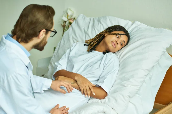 Médico de casaco branco segurando mão de mulher americana africana triste, enfermaria privada, conceito de aborto espontâneo — Fotografia de Stock
