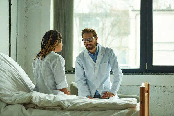 Male doctor talking to african american woman, explaining diagnosis, private ward, hospital — Stock Photo