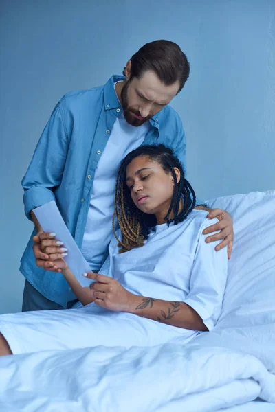 Triste homme debout près de femme afro-américaine, regardant l'échographie, hôpital, concept fausse couche — Photo de stock
