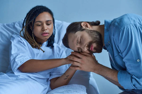 Fehlgeburtenkonzept, trauriger Mann trauert und hält Hand seiner afrikanisch-amerikanischen Frau, Krankenhausstation — Stockfoto