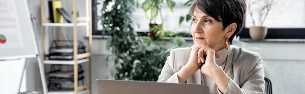 Experienced, pensive businesswoman looking away near laptop in office, decision making, banner — Stock Photo