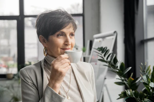 Donna di mezza età di successo, manager aziendale, bere caffè e distogliere lo sguardo in ufficio — Foto stock