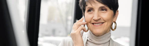 Fröhliche Geschäftsfrau mittleren Alters spricht auf Smartphone in modernen Büroräumen, Banner — Stockfoto