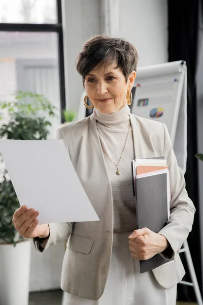 Empresária madura bem sucedida com pasta olhando para o documento no escritório, planejamento de negócios — Fotografia de Stock