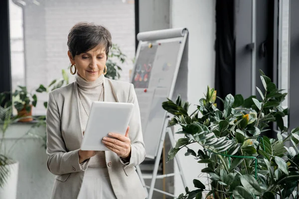 Selbstbewusste Geschäftsfrau mittleren Alters mit digitalem Tablet im modernen Büro, Geschäftsplanung — Stockfoto