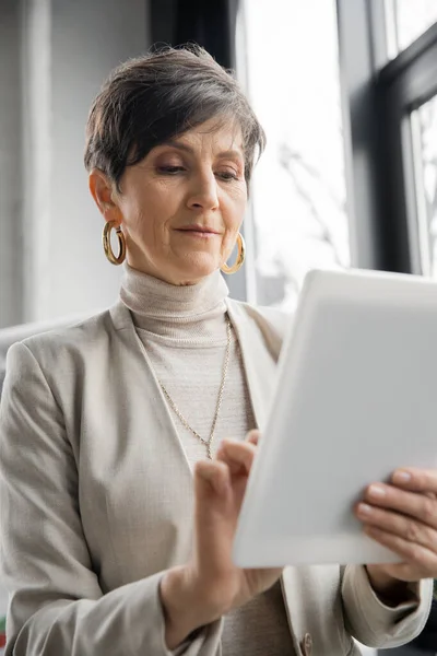 Entrepreneur d'âge moyen expérimenté utilisant une tablette numérique dans le bureau contemporain, l'âge dans la technologie — Photo de stock