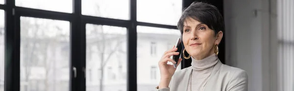 Nachdenklicher Manager mittleren Alters, der im Büro das Smartphone anruft und wegschaut, Banner — Stockfoto