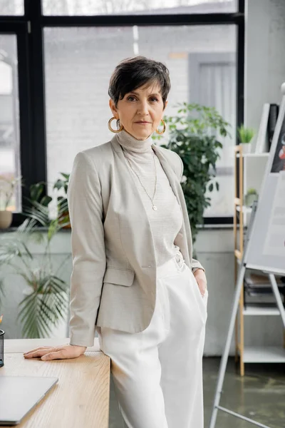 Experienced middle aged businesswoman with hand in pocket in modern office, headshot, portrait — Stock Photo