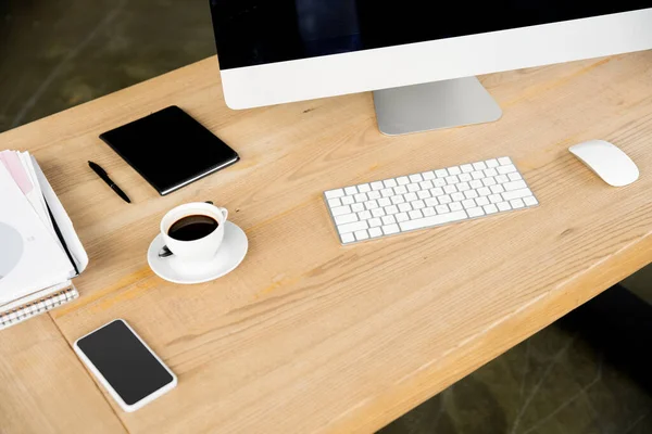Escritorio de oficina, taza de café, monitor de computadora, teclado, portátil, pluma, documentos, vista de ángulo alto - foto de stock