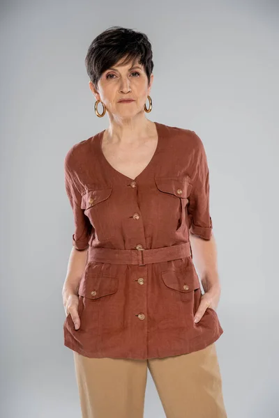 Tendance de la mode d'automne, brune femme mature en veste de lin marron regardant la caméra sur gris — Photo de stock