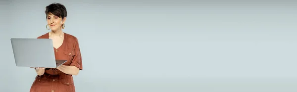 Brunetta donna d'affari in giacca marrone utilizzando il computer portatile su grigio, moda autunno, look elegante, banner — Foto stock