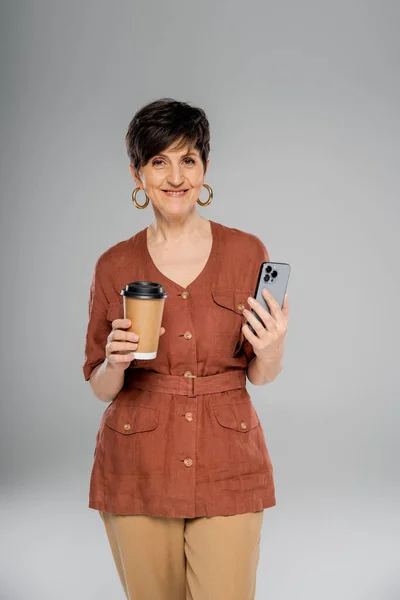 Geschäftsfrau mittleren Alters mit Smartphone und Pappbecher auf grauem, braunem Hemd, Herbstmode — Stockfoto