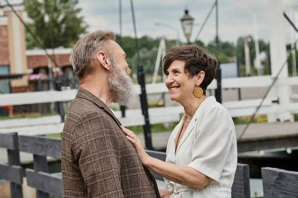 Feliz mujer mayor abrazando al hombre, mirándose al aire libre, el amor y el romance, pareja de ancianos - foto de stock