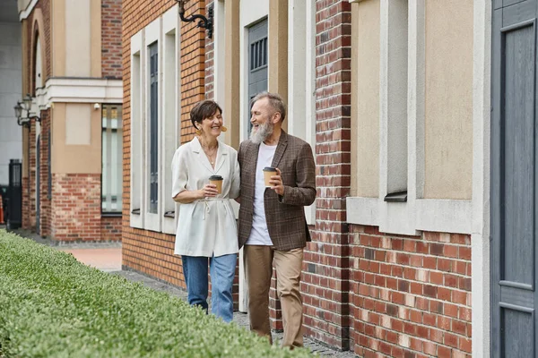 Glückliches älteres Paar mit Kaffee to go, zu Fuß in der Nähe von Gebäuden, Mann und Frau, ältere Menschen, Romantik — Stockfoto