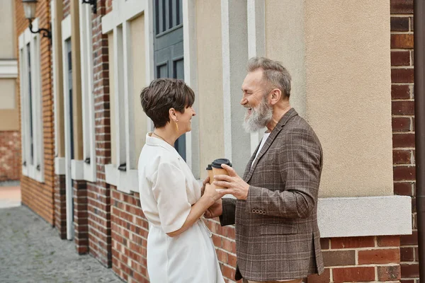 Glückliches Seniorenpaar, Coffee to go, Gebäude, älterer Mann und Frau, Lachen, einander anschauen — Stockfoto