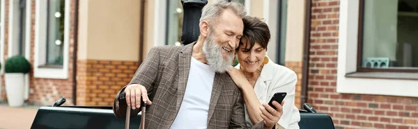 Баннер, пожилая пара, счастливый пожилой мужчина держит смартфон, сидя с женщиной с помощью гаджета — стоковое фото