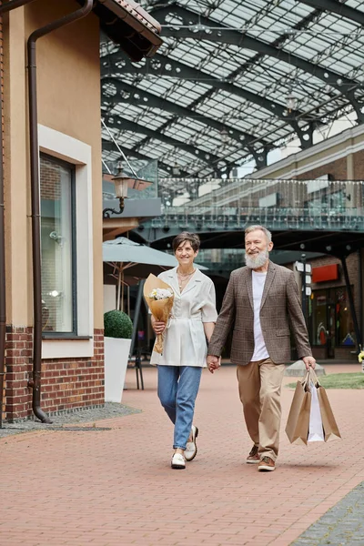 Glückliches älteres Paar, Einkaufen, Blumenstrauß, älteres Paar Händchenhalten, alternde Bevölkerung — Stockfoto