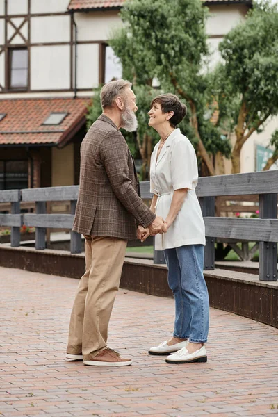 Woman and bearded man holding hands, date, senior romance, happy elderly couple, full length — Stock Photo